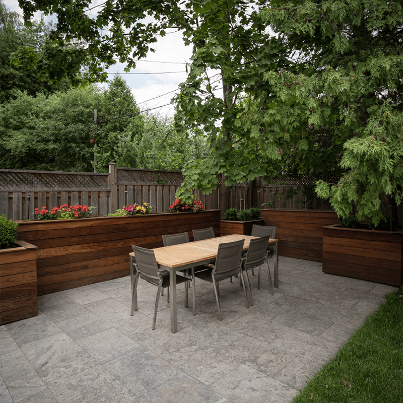 A tranquil backyard patio features a wooden table, surrounded by chairs, plants, and trees, enclosed by a wooden fence and lush greenery.